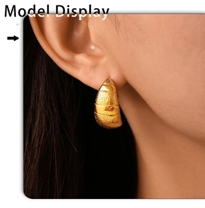 Gros plan d'une boucle d'oreille croissant dorée 18k avec finition mate sur un modèle