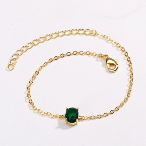 Close-up of gold-plated bracelet featuring an oval green zircon and adjustable lobster clasp