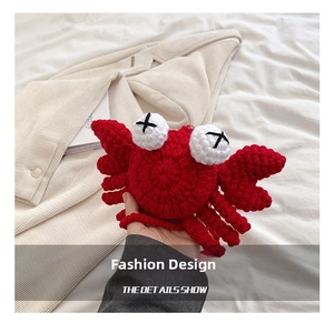 Macro detail of hand-knitted crab bag showing red yarn texture and cross-stitch eyes