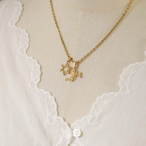 Detail of vintage gold plated necklace with star and angel pendants on a model