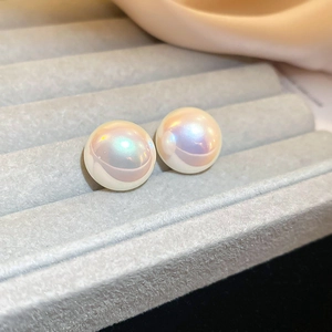 Close-up of iridescent mermaid pearl earrings on a gray velvet jewelry display