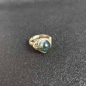 Detail of handmade gold wire-wrapped ring featuring a sphere green moss agate stone