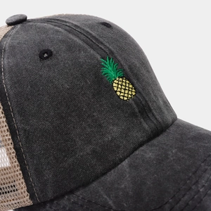 Close-up of pineapple embroidery on charcoal gray washed cotton and khaki mesh baseball cap