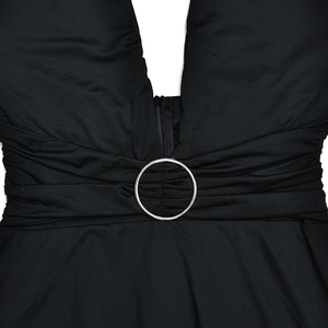 Detail of black halter dress featuring deep V-neck, silver ring, and pleated waist