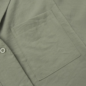 Detail of sage green shirt featuring high-quality stitching on a square pocket