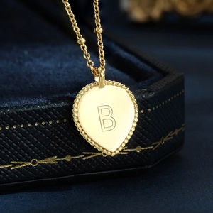 Macro shot of gold-plated pear-shaped pendant with letter B in a blue jewelry box