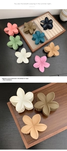 Detail of matte floral hair claw clips in various Morandi colors on a wooden tray