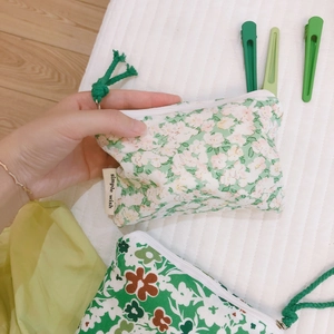 Green floral cotton coin purse with zipper and hand strap on white quilted background