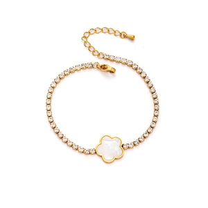Detailed macro view of gold chain bracelet with white flower pendant and zircon inlay