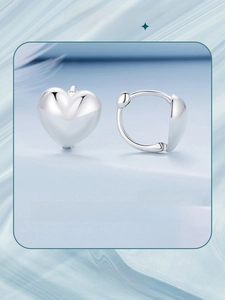 Macro shot of polished silver heart earrings featuring sleek 3D metallic texture and shine