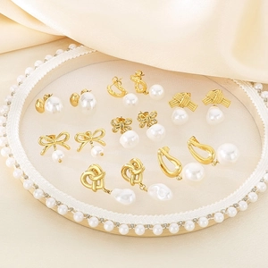 Elegant gold bow and pearl stud earrings set displayed on a white decorative tray