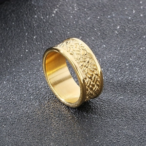 Detailed close-up of a wide gold-plated ring with intricate woven pattern on dark background