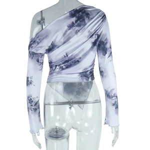 Détail de la blouse tie-dye à fleurs montrant la coupe épaule nue et l'ourlet