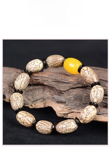 Makroaufnahme eines Bodhi-Samen-Armbands mit Bernsteinperle auf altem Holz