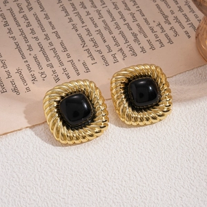 Detail of vintage square gold stud earrings with black stone on an open book