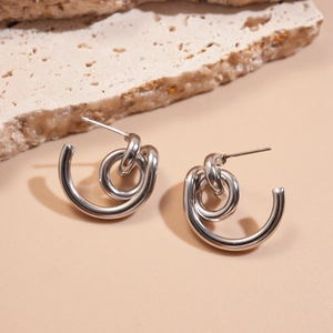 Macro view of silver geometric double-loop knot earrings with a polished metallic finish