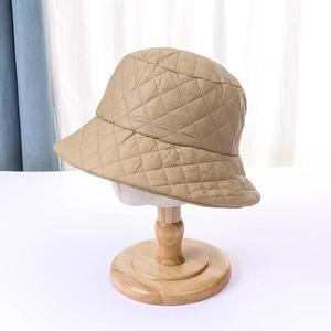 Detailed close-up of khaki quilted bucket hat with diamond stitching on a wooden stand