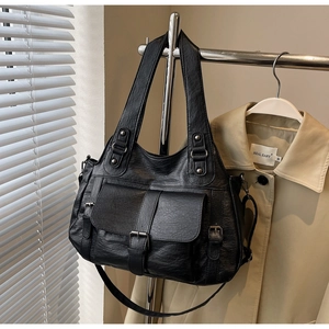 Detail of a black textured leather large capacity tote bag hanging on a metal hanger
