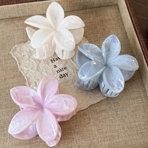 Pastel floral hair claws in mint, blue, and pink marble finish on a textured tray