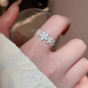 Détail d'une bague florale en émail avec pétales roses et bleus sur dentelle blanche