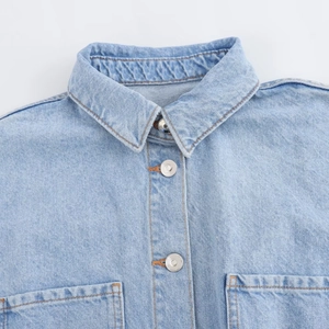 Detail of light blue denim romper collar with silver buttons and premium stitching