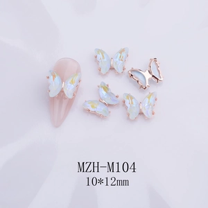 Vista macro de dijes de mariposa 3D para uñas en cristal blanco irisado y oro rosa