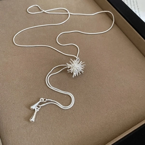 Detailed close-up of a silver zircon starburst pendant on a sleek snake chain necklace