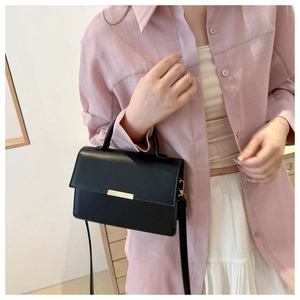 Détail d'un sac bandoulière noir avec texture cuir mat et accents métalliques dorés