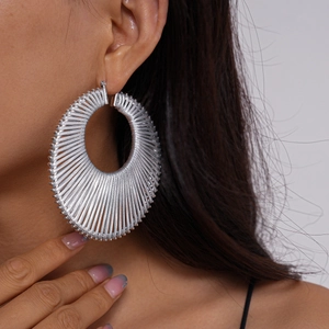 Close-up of a silver woven geometric round hoop earring shown on a model side view