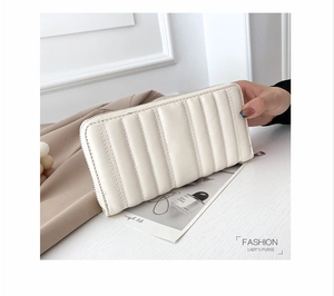 Portafoglio lungo bianco trapuntato da donna con cerniera tenuto in mano