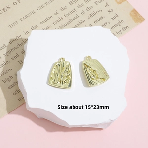 Detail of golden rectangular plant leaf pendants with size 15x23mm on a stone platform