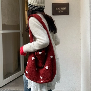 Detailed view of red plush tote bag with white hearts and wide shoulder strap