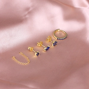 Detail of S925 sterling silver gold-plated earring set with blue stones on pink satin
