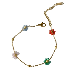 Gold chain bracelet with five colorful floral charms and metallic beads on white background