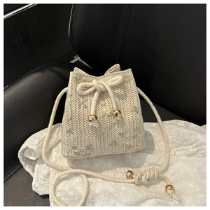 Detail of woven straw bucket bag with floral embroidery and cotton drawstring cord