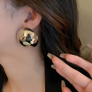 Side view of model wearing large polished silver hoop earrings with a mirror finish surface