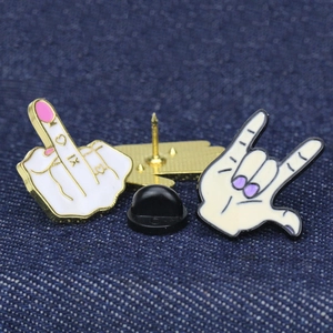 Punk rock hand gesture enamel pins with heart detail on blue denim fabric background