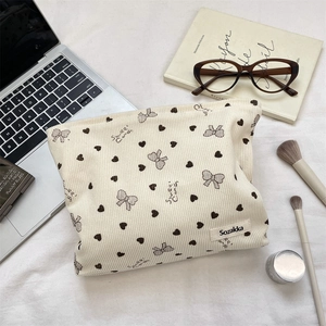 Dettaglio della borsa trucco in velluto a coste beige con cuori e fiocchi stampati