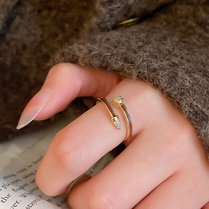 Detail shot of a gold pony ring with zircon stones on a female hand against a warm background
