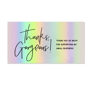 Close-up of holographic laser rainbow thank you cards with black typography on white surface