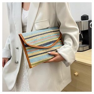 Detailed view of colorful striped straw envelope clutch with brown leather trim detailing