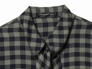 Detail view of green plaid shirt neckline with ZEAL WOMAN brand label and size tags