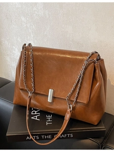 Brown vintage faux leather tote bag with silver chain strap on a minimalist background