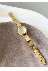 Detail of luxury gold quartz watch with Roman numerals on elegant purple knit fabric