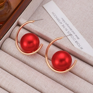 Close-up of vintage gold hoop earrings with large red pearls in a jewelry display box