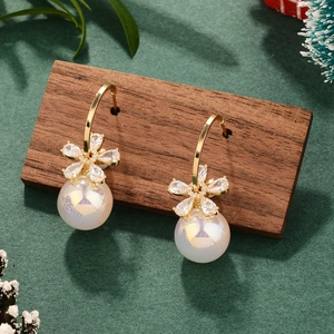 Close-up of French vintage pearl earrings with gold floral crystal details on green background