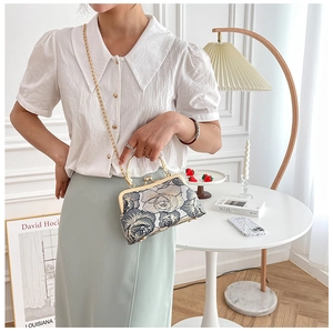 Floral cheongsam handbag with gold handle and chain strap shown in a lifestyle setting