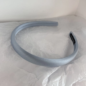 Detailed macro view of a light blue satin padded headband with a handmade inner label