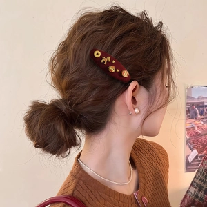 Detail of red velvet hair clip with golden zodiac horse and traditional lucky charms