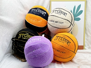 Close-up of assorted plush basketball pillows in a wire basket with detailed embroidery
